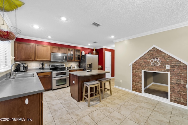 kitchen featuring ornamental molding, sink, appliances with stainless steel finishes, and a center island