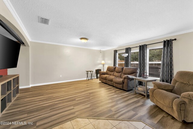 living room featuring wood-type flooring, crown molding, and a textured ceiling