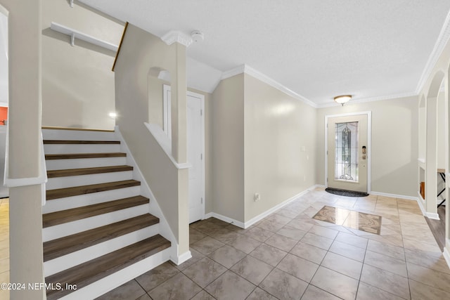 foyer entrance featuring a textured ceiling and crown molding