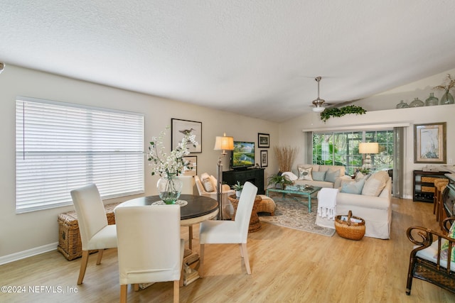 dining room featuring light hardwood / wood-style flooring, a textured ceiling, lofted ceiling, and ceiling fan