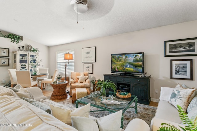 living room with a textured ceiling, wood-type flooring, and ceiling fan