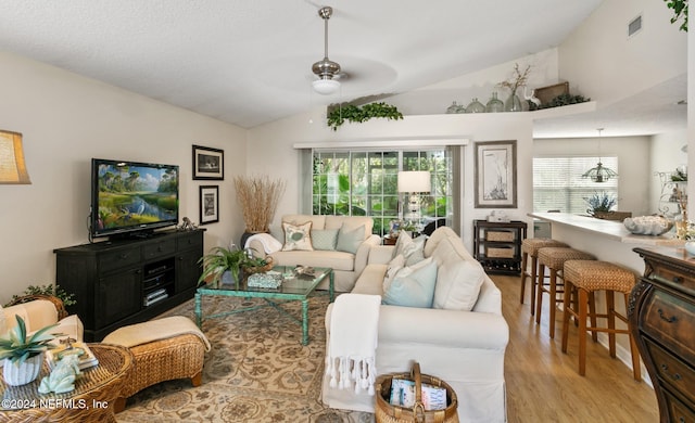 living room with light hardwood / wood-style floors, ceiling fan, and vaulted ceiling