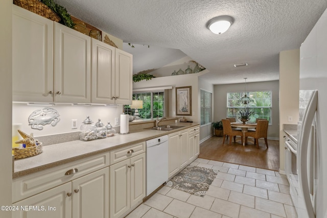 kitchen featuring sink, white dishwasher, light hardwood / wood-style floors, lofted ceiling, and pendant lighting