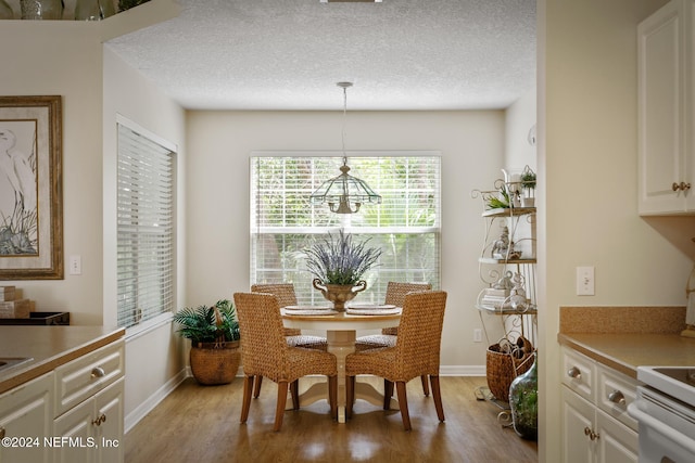 dining area with a textured ceiling, an inviting chandelier, and light wood-type flooring