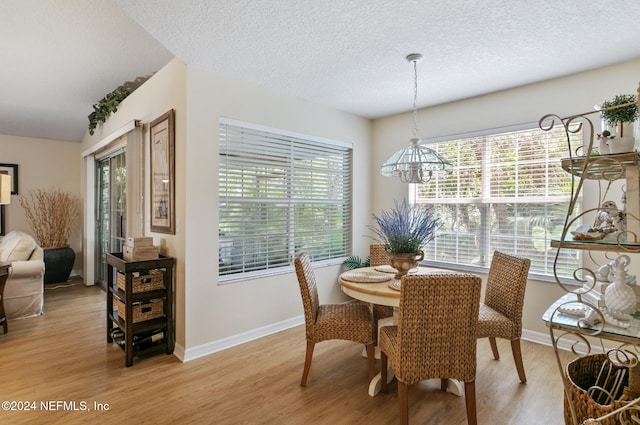 dining room featuring an inviting chandelier, light hardwood / wood-style flooring, and a textured ceiling