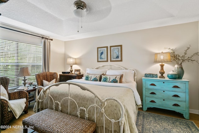 bedroom featuring dark hardwood / wood-style flooring, a textured ceiling, and ceiling fan