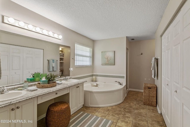 bathroom with vanity, a textured ceiling, a bathtub, and tile patterned flooring