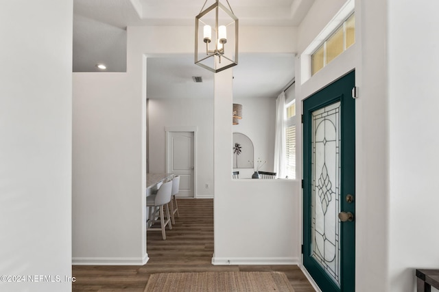 foyer with dark wood-type flooring and an inviting chandelier