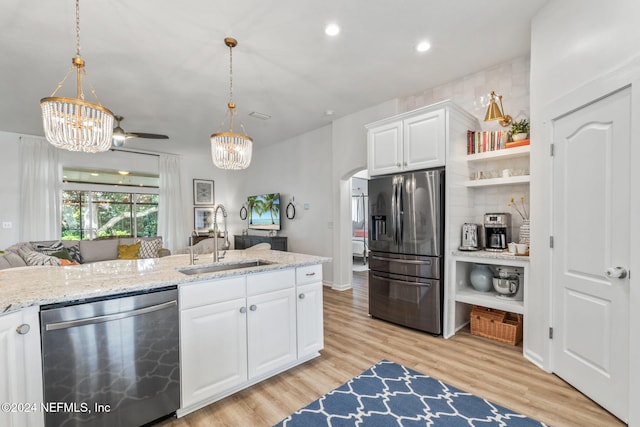 kitchen featuring appliances with stainless steel finishes, white cabinetry, light hardwood / wood-style floors, decorative light fixtures, and sink