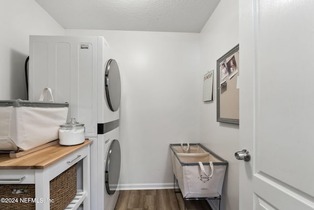 clothes washing area featuring a textured ceiling, stacked washer and dryer, and dark hardwood / wood-style floors