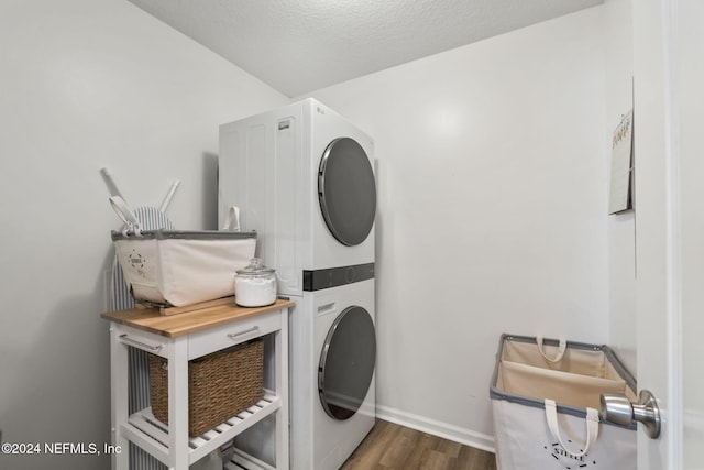 laundry area featuring a textured ceiling, stacked washer / dryer, and dark wood-type flooring