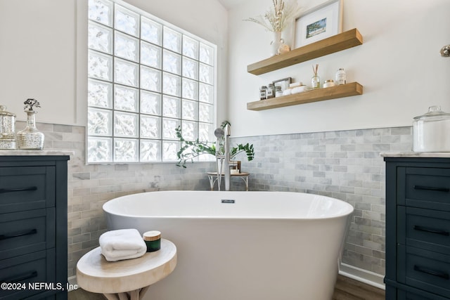 bathroom with tile walls, vanity, plenty of natural light, and a washtub