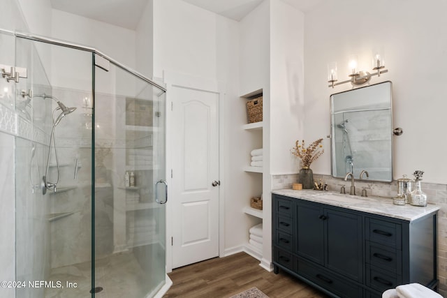 bathroom with vanity, decorative backsplash, a shower with door, and hardwood / wood-style floors