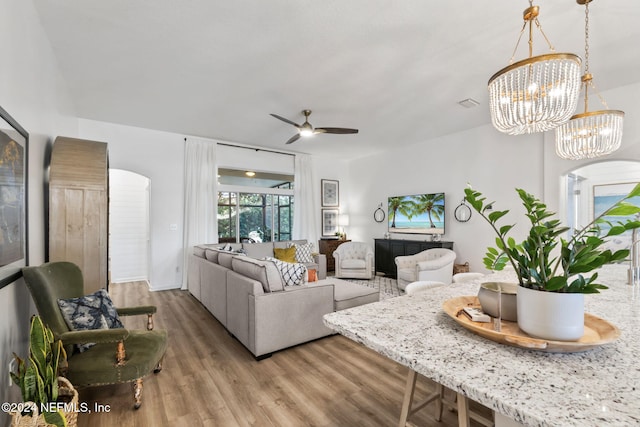 living room with hardwood / wood-style flooring and ceiling fan with notable chandelier