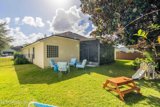 back of house featuring a sunroom and a lawn