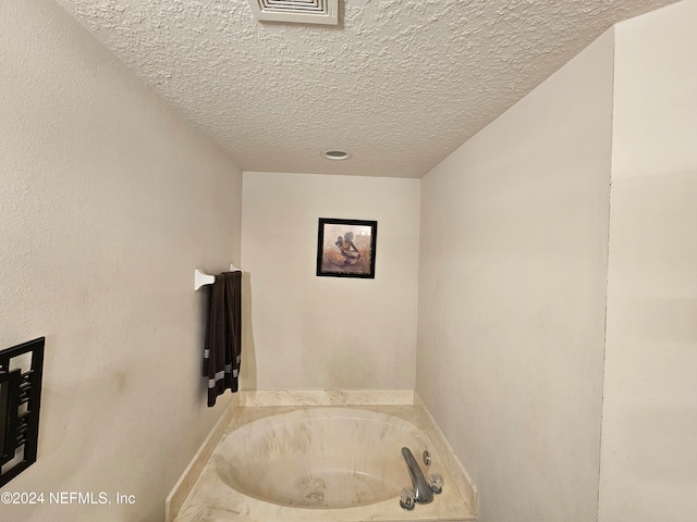 bathroom featuring a bath and a textured ceiling