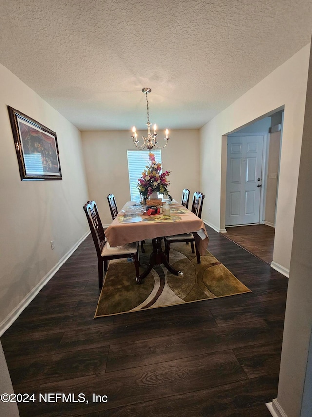 dining space featuring a notable chandelier, a textured ceiling, and dark wood-type flooring