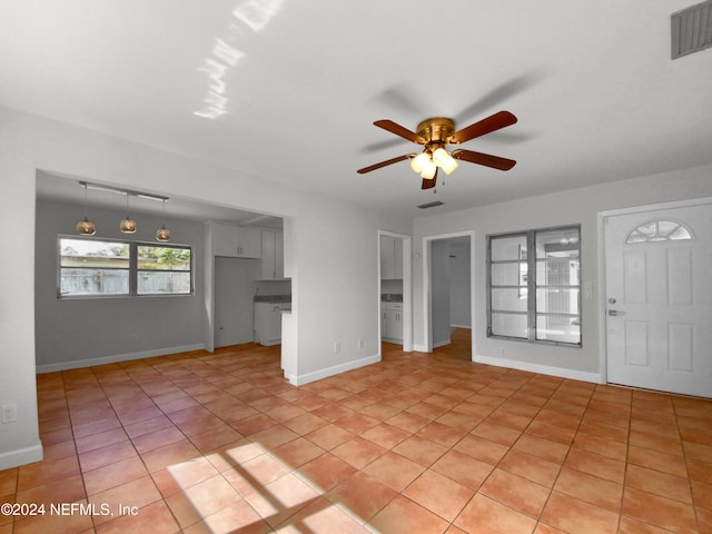 unfurnished living room featuring light tile patterned floors and ceiling fan