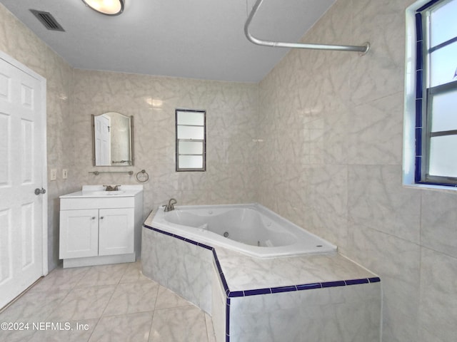 bathroom with vanity, a relaxing tiled tub, and tile walls