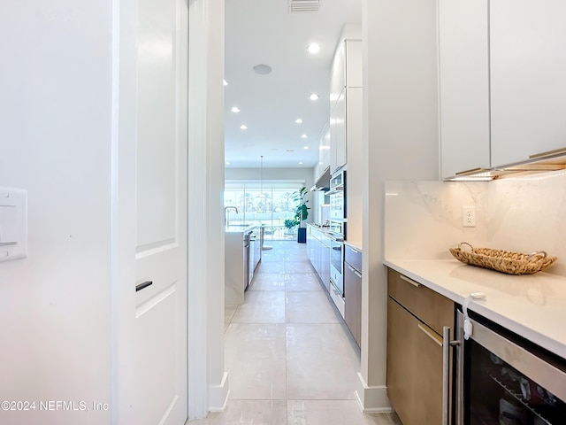 corridor featuring light tile patterned flooring, sink, and wine cooler