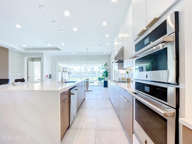 kitchen with sink, a spacious island, extractor fan, white cabinets, and appliances with stainless steel finishes