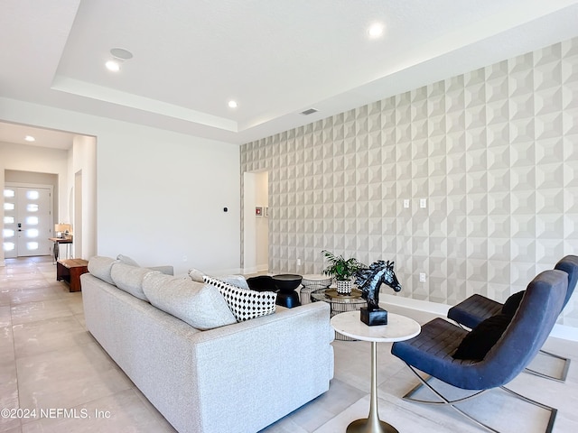 living room with a raised ceiling and tile walls