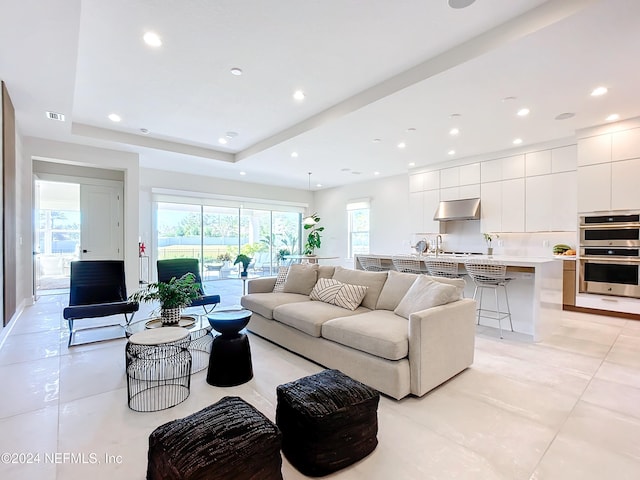 living room featuring a tray ceiling and light tile patterned flooring