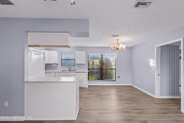 kitchen with white cabinets, pendant lighting, white appliances, and light hardwood / wood-style floors