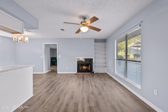 unfurnished living room with ceiling fan with notable chandelier, hardwood / wood-style floors, and a textured ceiling