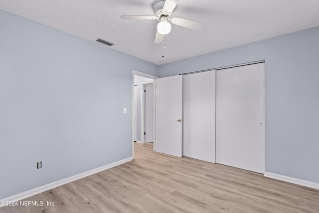 unfurnished bedroom featuring a textured ceiling, a closet, light hardwood / wood-style floors, and ceiling fan