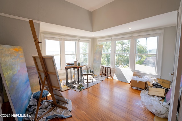 interior space with light wood-type flooring, a towering ceiling, a healthy amount of sunlight, and crown molding