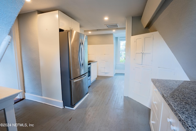 kitchen with dark wood-type flooring, white cabinetry, dark stone counters, and stainless steel appliances