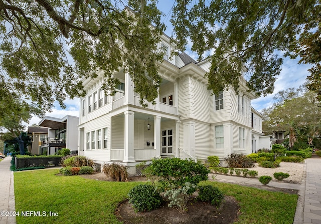 greek revival house with a porch, a front lawn, and a balcony