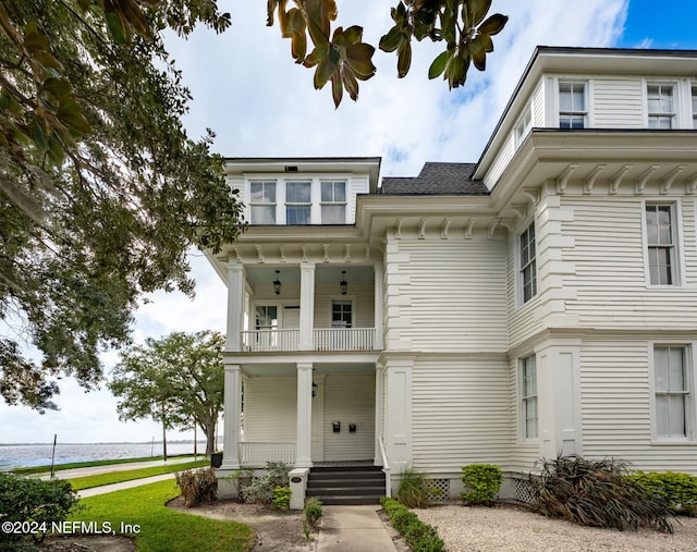 view of front of home featuring a porch, a water view, and a balcony