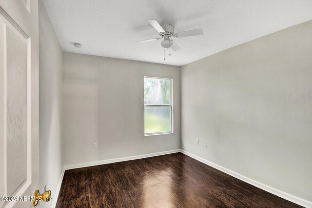 empty room with a textured ceiling, dark wood-type flooring, and ceiling fan