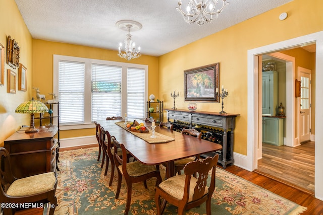 dining area featuring hardwood / wood-style flooring, a textured ceiling, and an inviting chandelier