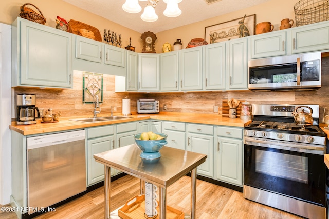 kitchen featuring decorative backsplash, wood counters, sink, light hardwood / wood-style floors, and stainless steel appliances