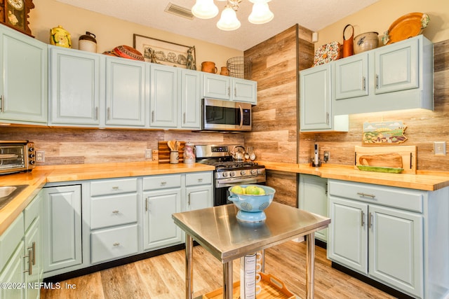 kitchen featuring a textured ceiling, butcher block countertops, light hardwood / wood-style flooring, and stainless steel appliances