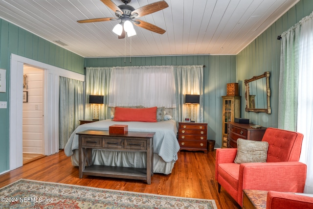 bedroom with ceiling fan, wood walls, wooden ceiling, and hardwood / wood-style floors