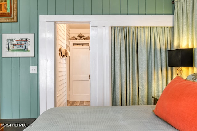 bedroom featuring a closet, wood walls, and hardwood / wood-style floors