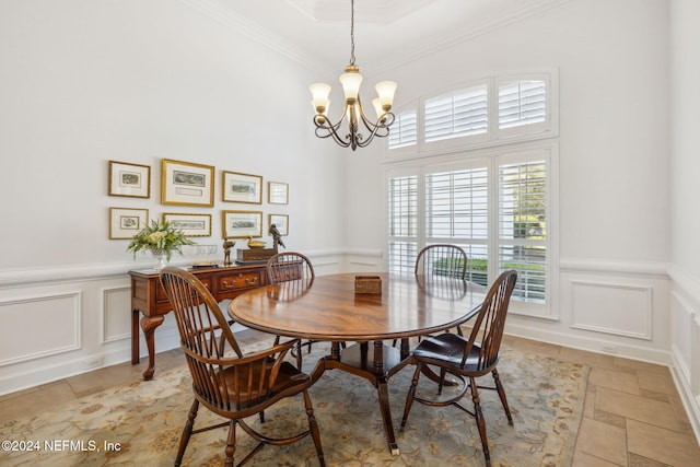 dining area featuring a high ceiling, a chandelier, and crown molding