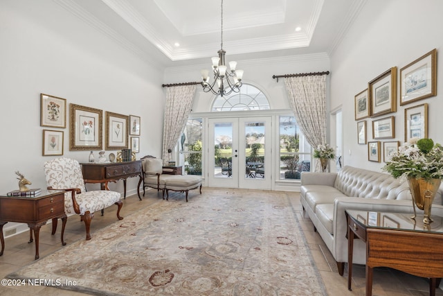 living room with french doors, crown molding, a towering ceiling, a notable chandelier, and a raised ceiling