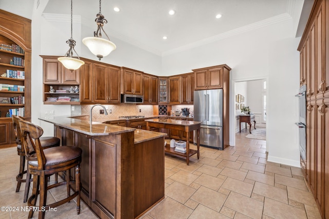 kitchen featuring stone countertops, a high ceiling, appliances with stainless steel finishes, backsplash, and decorative light fixtures