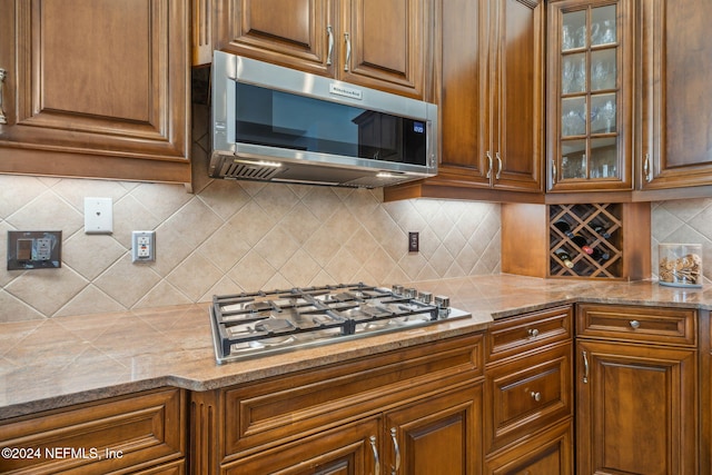 kitchen featuring light stone countertops, appliances with stainless steel finishes, and tasteful backsplash