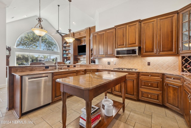 kitchen with decorative backsplash, hanging light fixtures, sink, ceiling fan, and appliances with stainless steel finishes