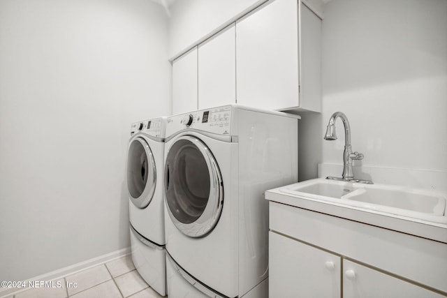 laundry area with cabinets, washer and clothes dryer, sink, and light tile patterned flooring