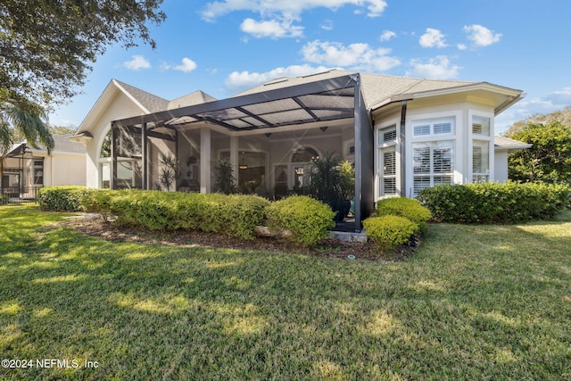 rear view of house featuring a lawn and a lanai