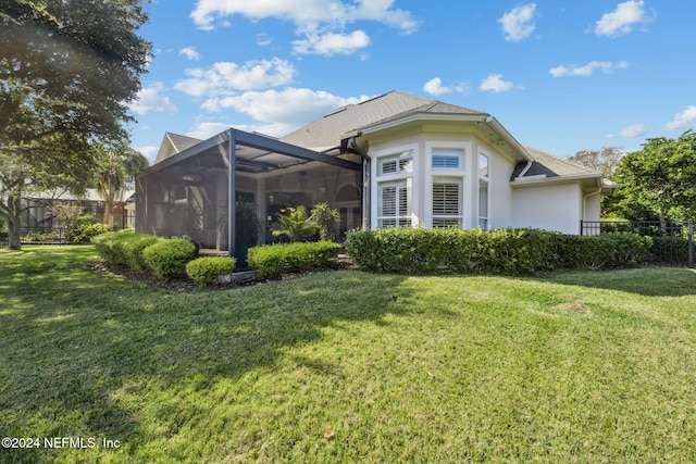 rear view of property with a lawn and glass enclosure