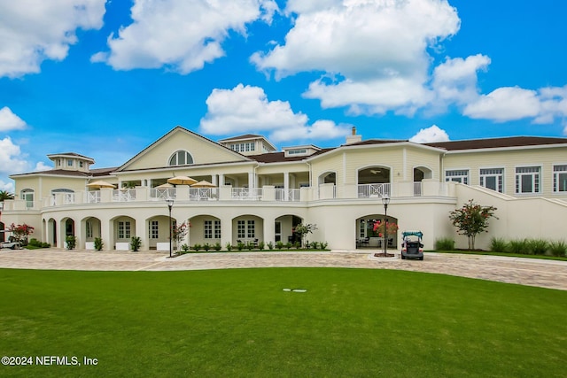 back of house featuring a lawn, a balcony, and a patio area