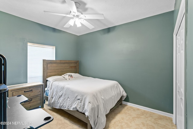 tiled bedroom with ceiling fan and a closet